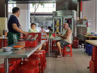 Mr Tay, on the left, interacts with a British tourist couple in his kopitiam (Helen Jambunathan, 2017) Mr Tay, on the left, interacts with a British tourist couple in his kopitiam (Helen Jambunathan, 2017)